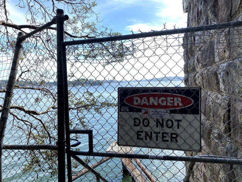 A sign that says 'danger: do not enter' with the ocean in the background