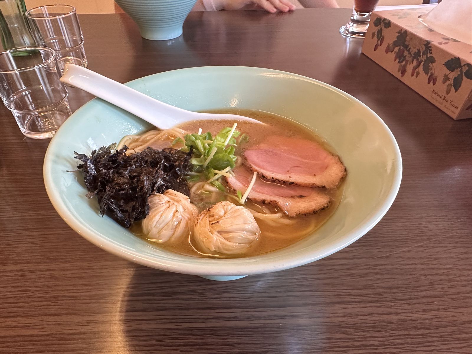 A photo of a bowl of ramen, with two pieces of cured duck meat and some small tofu skin balls 