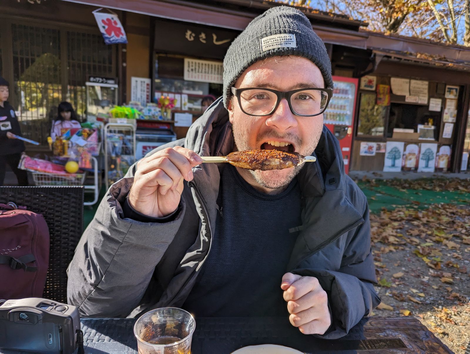 A photo of a man smiling with a stick of shohei mochi, about to eat it